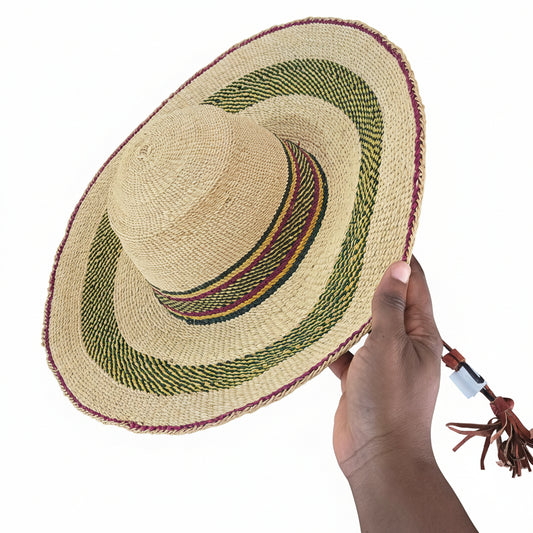 Hand holding a woven straw hat with a decorative band on a textured surface