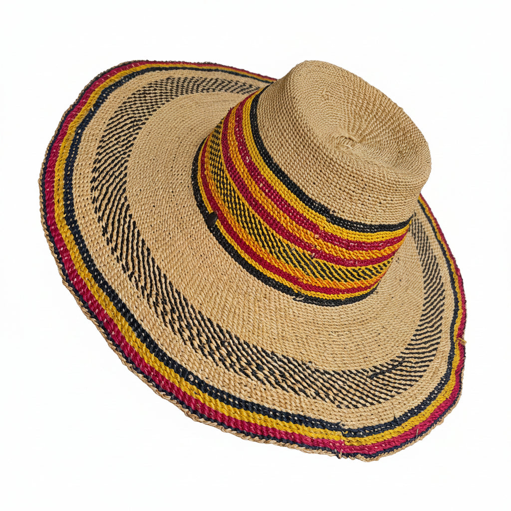 A natural straw sun hat with a wide brim, featuring woven stripes of black, red, yellow, and beige around the crown and brim edge, shown being worn on a person's head.