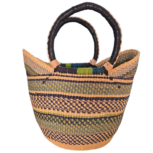 A hand-woven basket bag with dark brown twisted handles, featuring vertical stripes of black, beige, and olive green on a woven body, photographed on a desk.