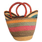A woven straw tote bag with vertical stripes in black, orange, pink, teal, and beige, featuring two thick, reddish-brown handles.