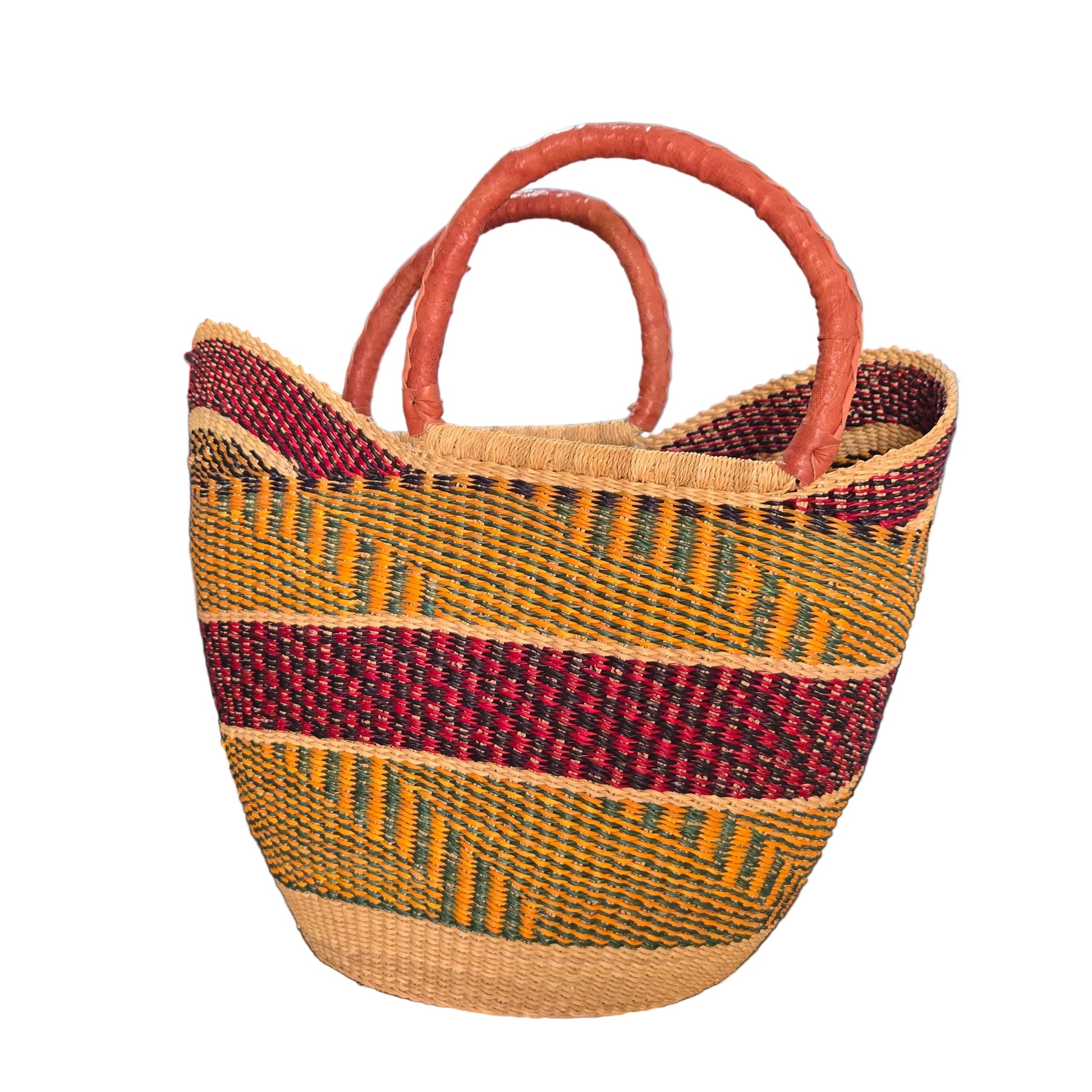 A woven basket bag with two curved handles, featuring a natural beige base, a vertical dark red stripe, and horizontal stripes of yellow, green, and red. The bag is photographed on a desk with a blue binder and office items in the background.