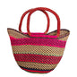 A woven straw tote bag with vibrant pink, red, green, and black stripes, featuring two thick reddish-brown handles.